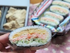 a person holding up a sushi in front of some other foods on the table