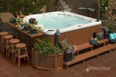 an outdoor hot tub surrounded by potted plants and bar stools on brick patio