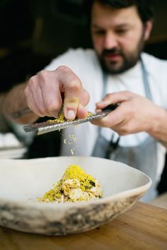 a man is sprinkling seasonings in a bowl on a wooden counter top