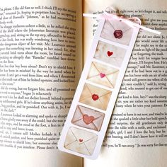 an open book with four envelopes on it and some hearts in the pages,