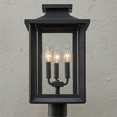 three candles are lit in an old - fashioned light fixture on a street lamp post