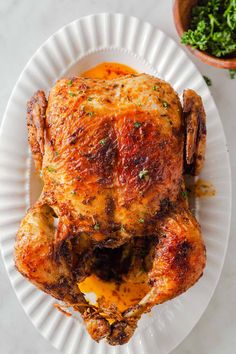 a whole chicken on a paper plate with sauce and parsley