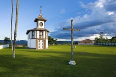 a small white and brown building with a cross in the grass