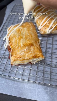 a pastry being drizzled with icing on top of a cooling rack