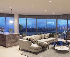 a living room filled with furniture and large windows overlooking the city at night in the distance