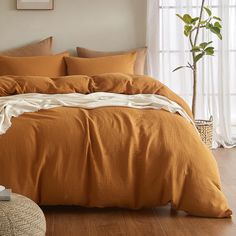 a bed with an orange comforter and pillows