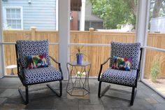 two chairs sitting on top of a patio next to a table