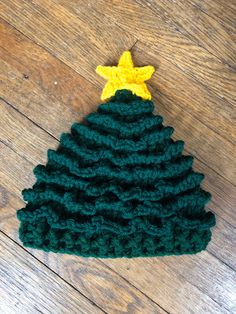 a green crocheted christmas tree with a yellow star on top sitting on a wooden floor