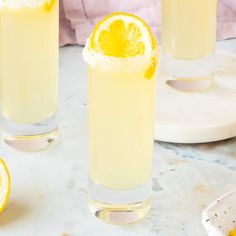 two glasses filled with lemonade sitting on top of a table