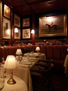 a dining room with tables and chairs covered in white tablecloths, framed pictures on the wall