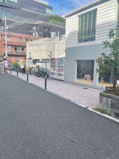 people are walking down the street in front of some buildings with bicycles parked on the sidewalk