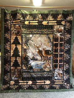 a quilted wall hanging with deer in the woods on it's sides and an arrow at the bottom