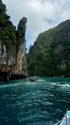 a boat is traveling through the water near some mountains and trees on either side of it