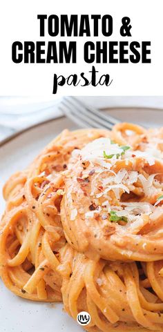 a white plate topped with pasta covered in tomato sauce and parmesan cheese on top