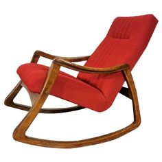 a wooden rocking chair with red upholstered fabric on the back and seat cushion