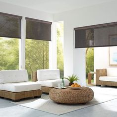 a living room filled with white furniture and large windows covered in blind shades on top of them