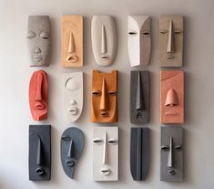 several different colored masks are arranged on a white wall, each with their own face