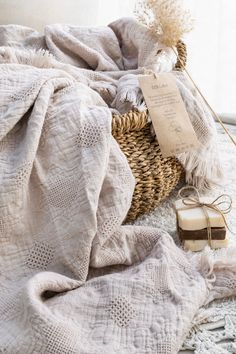 a basket filled with items sitting on top of a white bed next to a blanket