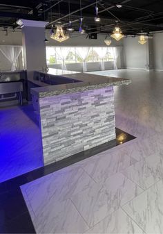 an empty dance studio with lights on the ceiling and white marble counter tops in the center