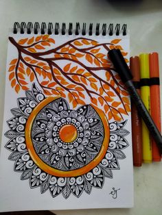 an orange and black drawing on paper next to crayons