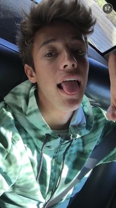 a young man sticking his tongue out in the back seat of a car