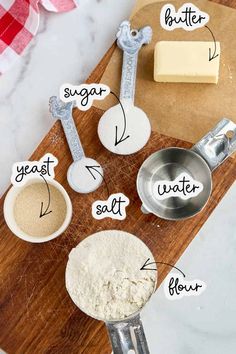 ingredients to make homemade buttered biscuits on a cutting board with measuring spoons and flour