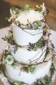 a three tiered cake with flowers and greenery on top