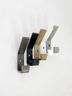 four different colored metal brackets on a white wall