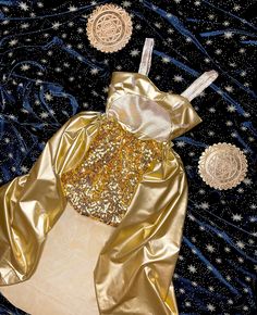 a golden dress with gold sequins on it and stars in the sky above