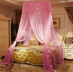 a purple canopy bed in a bedroom with white furniture and lights on the headboard