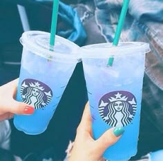 two people holding up starbucks cups with green straws