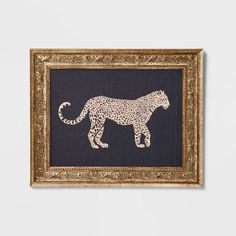 a white and black animal in a gold frame on a wall next to a gray wall