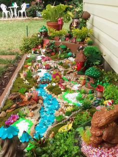 a garden filled with lots of different types of plants and rocks on the ground next to a house