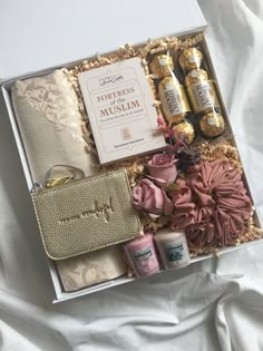 the contents of a gift box are laid out on a white sheet with pink and gold accessories