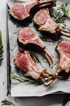 raw lamb chops on parchment paper with rosemary sprigs