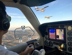 a man in the cockpit of an airplane with headphones on looking at a computer screen