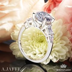 two diamond engagement rings sitting on top of a flower