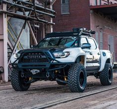 a white toyota truck parked on the side of a road next to a red brick building