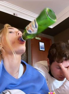 a man and woman are drinking beer from a bottle while laying on the floor in front of them