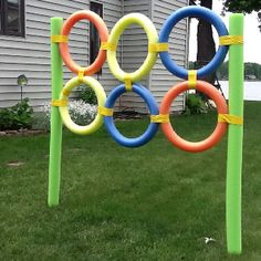 an olympic sign made out of plastic rings in front of a house with grass and flowers