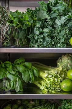 fresh vegetables are displayed on metal shelves in a grocery store, including broccoli, lettuce and limes