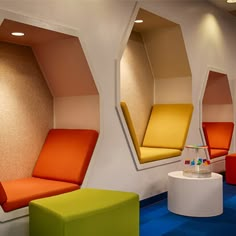 colorful chairs and tables in a room with mirrors on the wall behind them that are shaped like hexagonal shapes