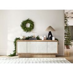 a living room with christmas decorations and wreaths on the wall above it, along with a white rug