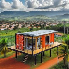 a house made out of shipping containers on top of a hill with palm trees and mountains in the background