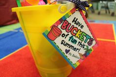 there is a yellow cup with straws in it and a sign that says have buckets of fun this summer