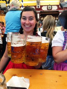 two women holding up beer glasses at a table