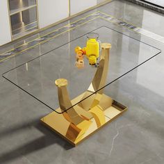 a glass table with some yellow items on it in the middle of an empty room