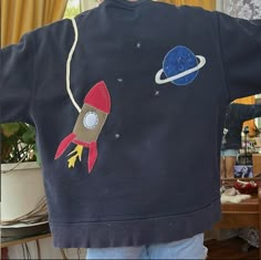 a child's sweatshirt with an image of a rocket ship on it