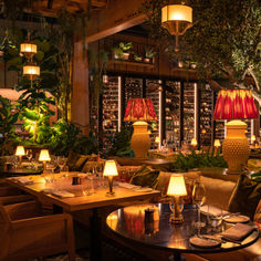 a restaurant with lots of tables and chairs in front of large windows filled with plants