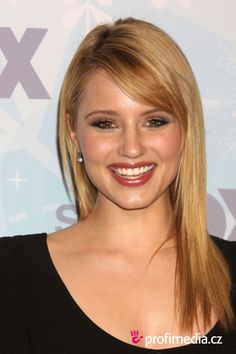 a woman with long blonde hair smiling at the camera and wearing a black dress,